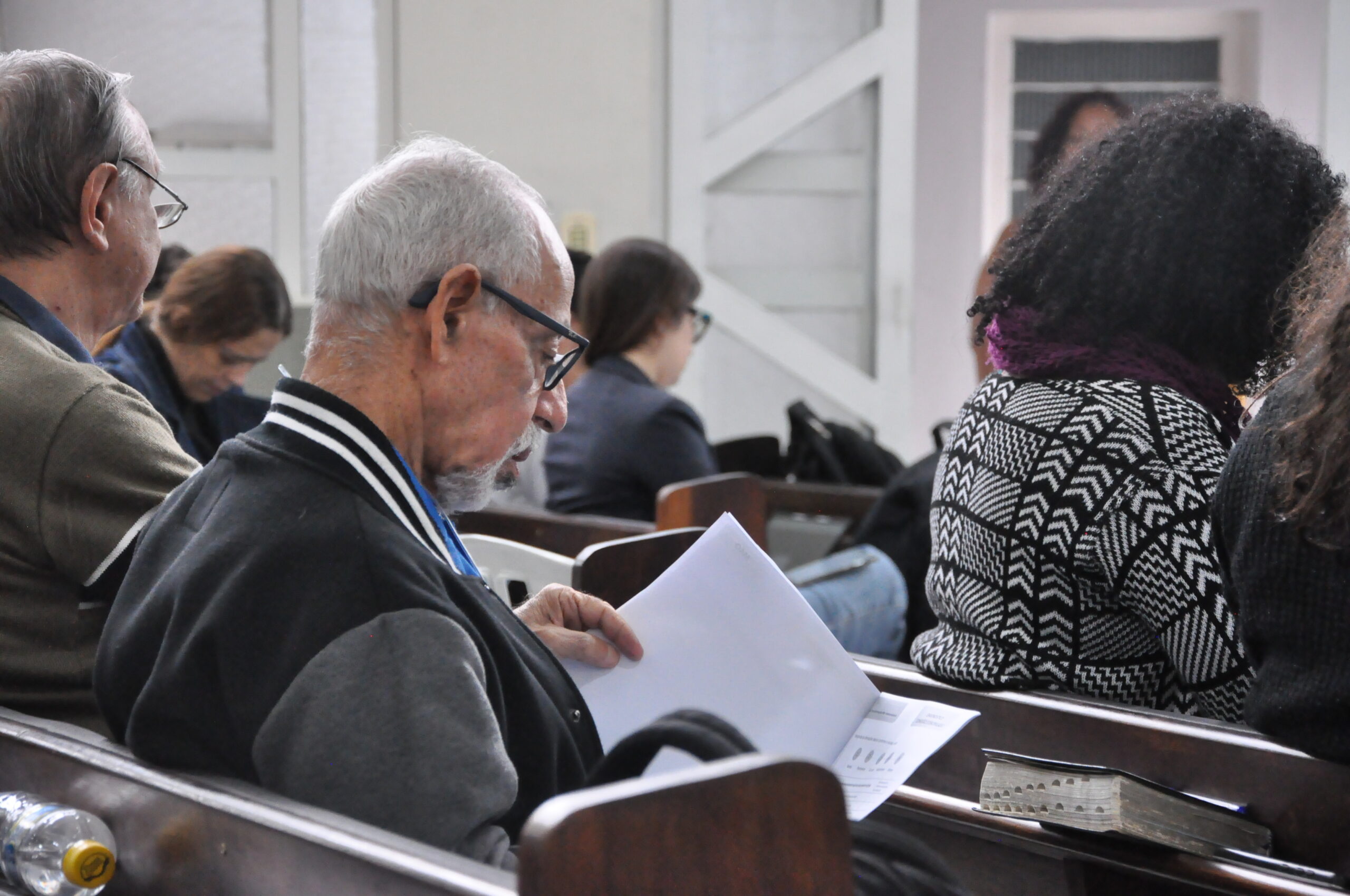 Homem idoso sentado e lendo.
